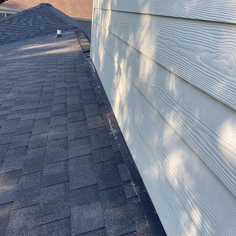 Asphalt shingle roof with wall flashing and siding panel