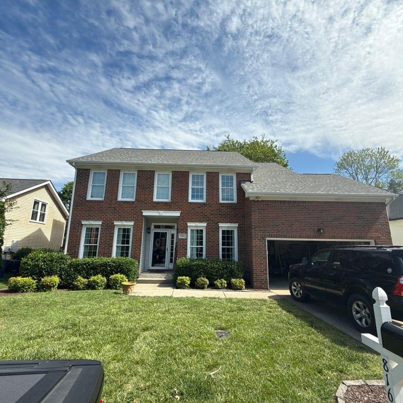 Roof shingles and ridge with hail damage on brick house