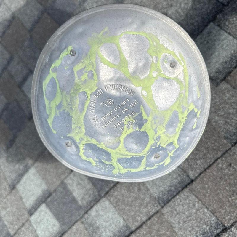 Roof vent cap with hail impact markings on shingles