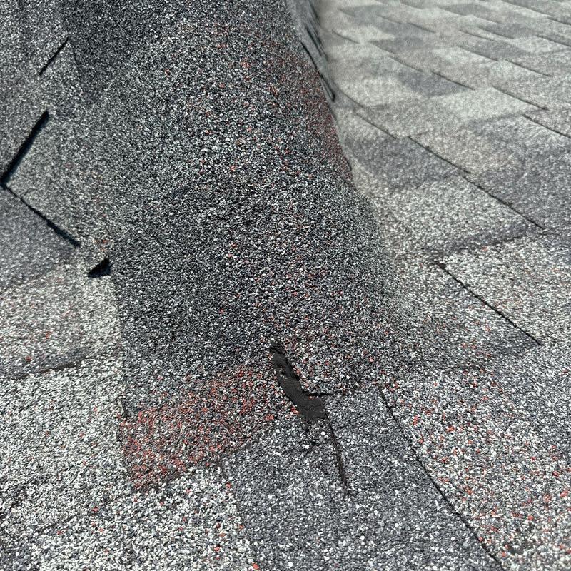 Asphalt roof shingles with hail damage near flashing
