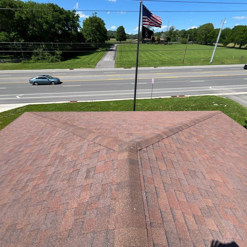 Asphalt shingle roof ridge cap inspection with flagpole view
