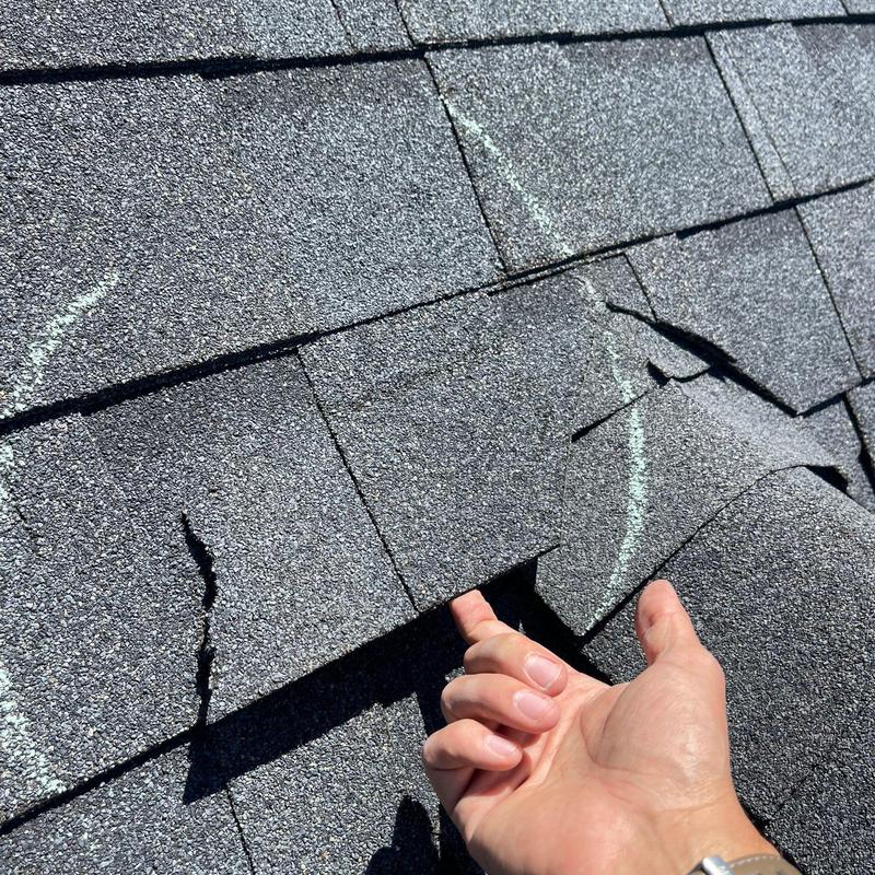Asphalt roof shingles with hail damage marked for repair