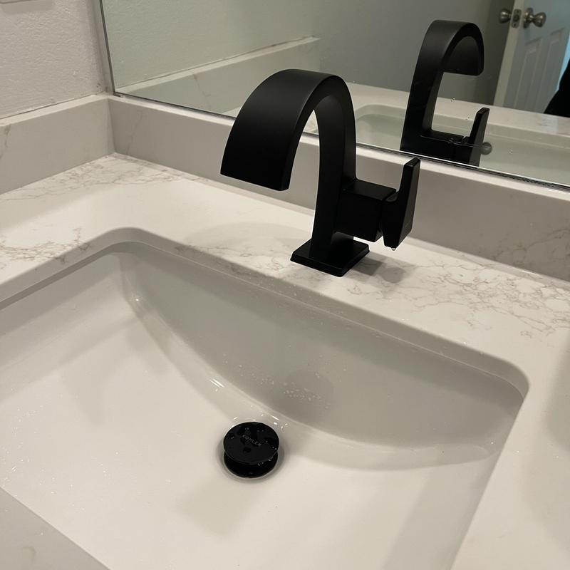Black bathroom faucet and pop-up drain in sink