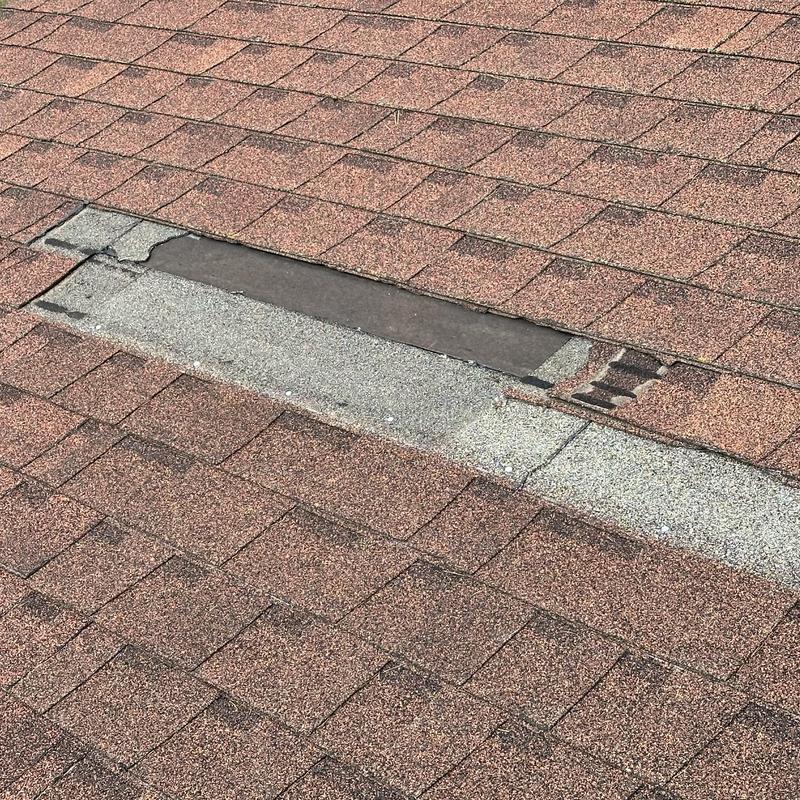 Asphalt roof shingles with missing section and damage