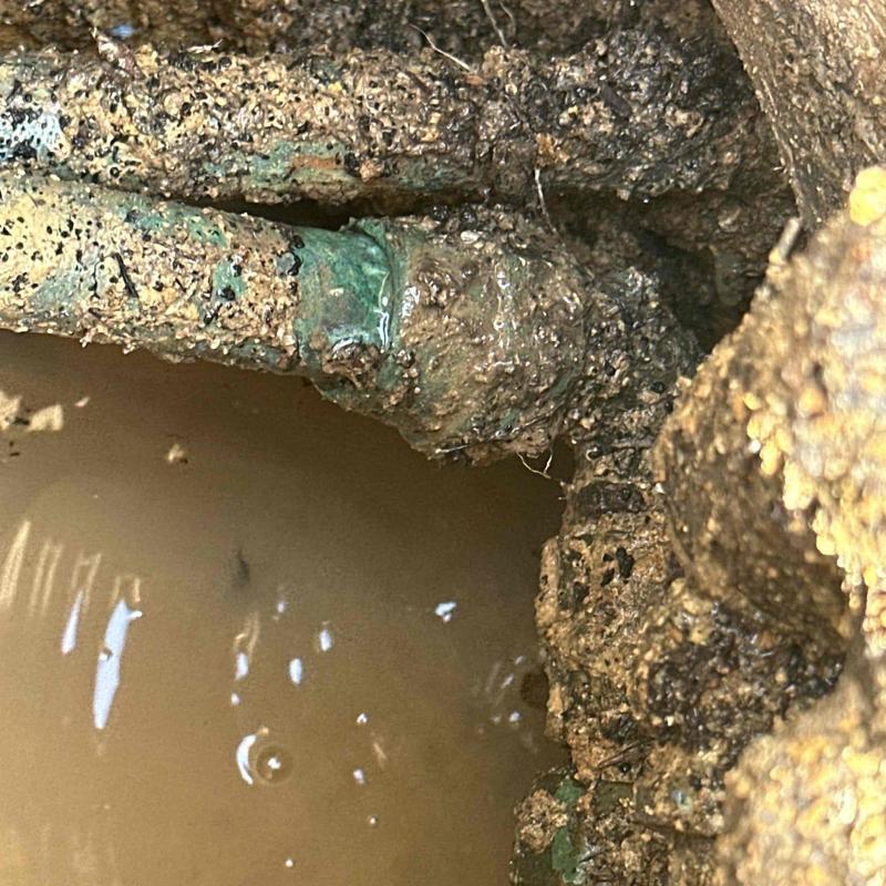 Corroded copper water line in muddy excavation site Corroded copper water line in muddy excavation site