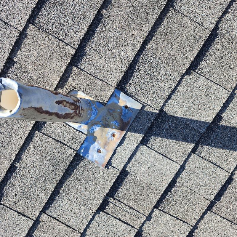 Roof pipe flashing with rusted metal base and exposed screws
