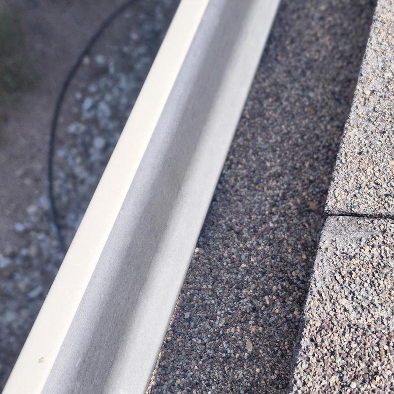 Shingle granules and gutter buildup on old roof edge