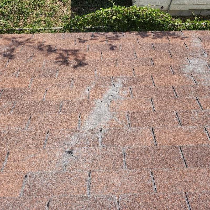 Roof shingles with wear and missing granules near hole Roof shingles with wear and missing granules near hole