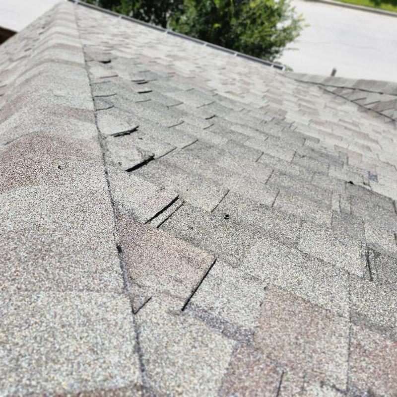 Asphalt shingle roof with exposed fasteners and damage