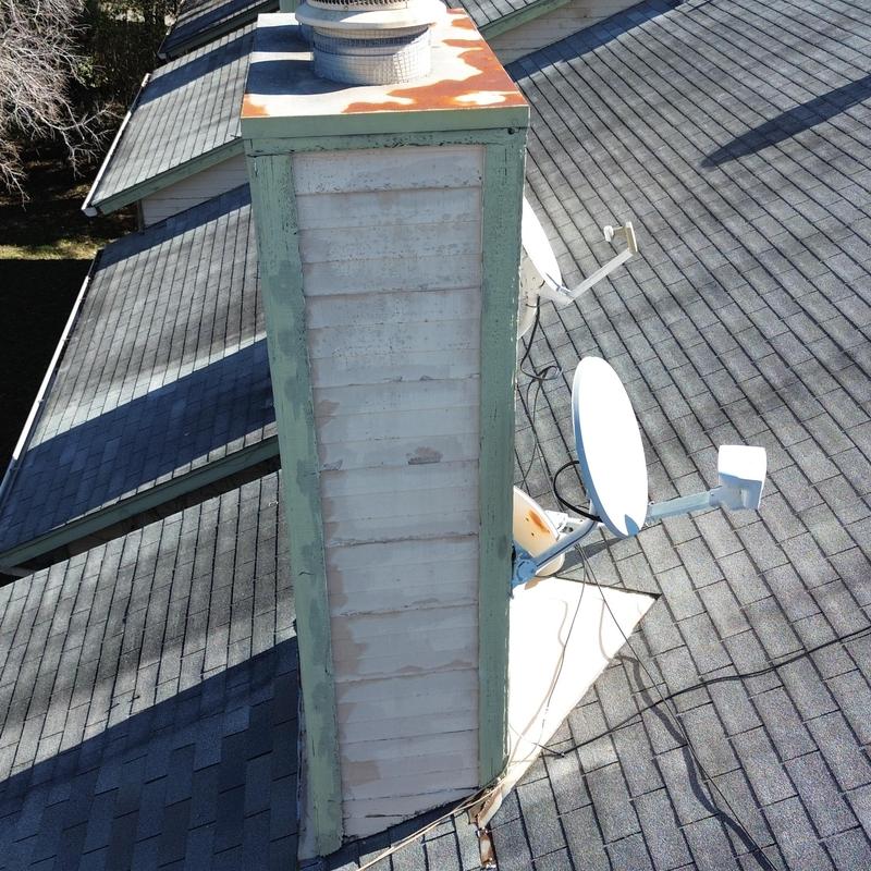 Rusted chimney chase and cricket on shingle roof