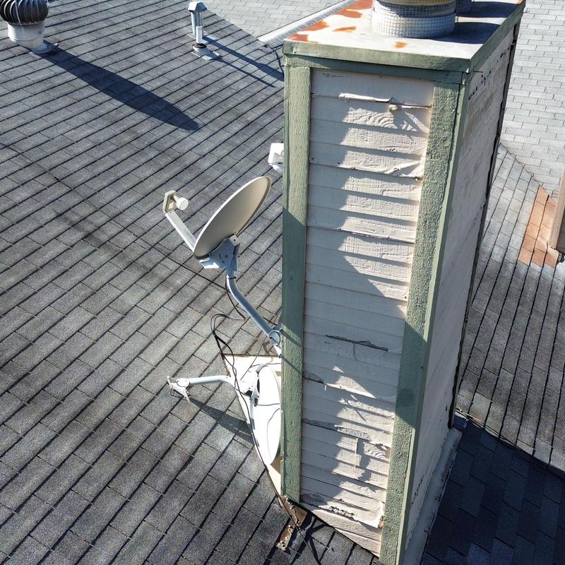 Chimney chase with rust and satellite dishes on roof