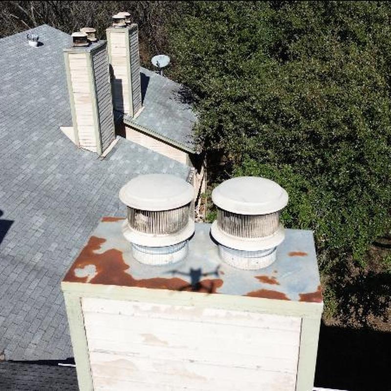 Rusty metal chimney chase with vent caps on roof