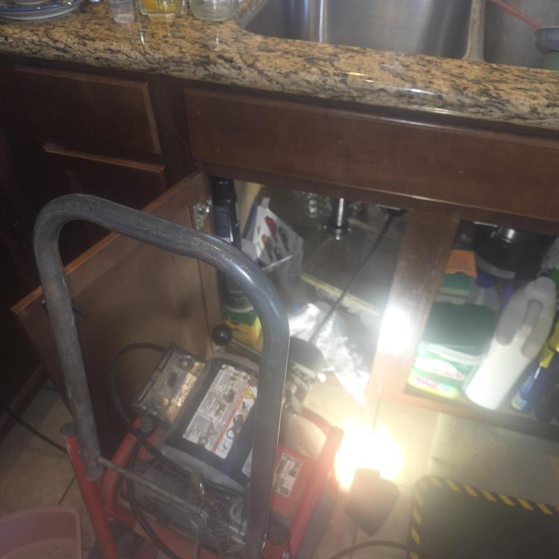 Kitchen sink drain snake clearing blockage under cabinet