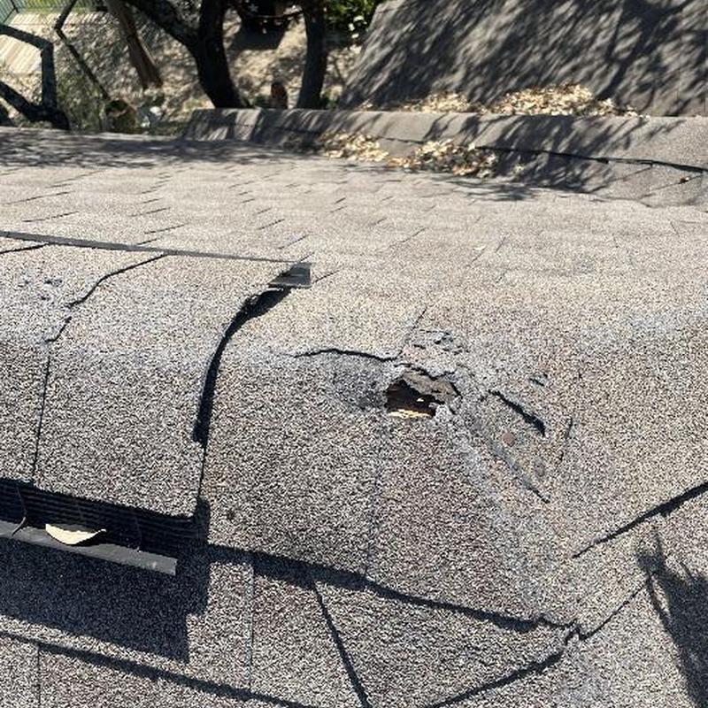 Damaged asphalt roof shingles with visible wear and tear