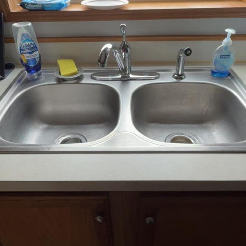 Kitchen faucet and double sink with soap and sponge.