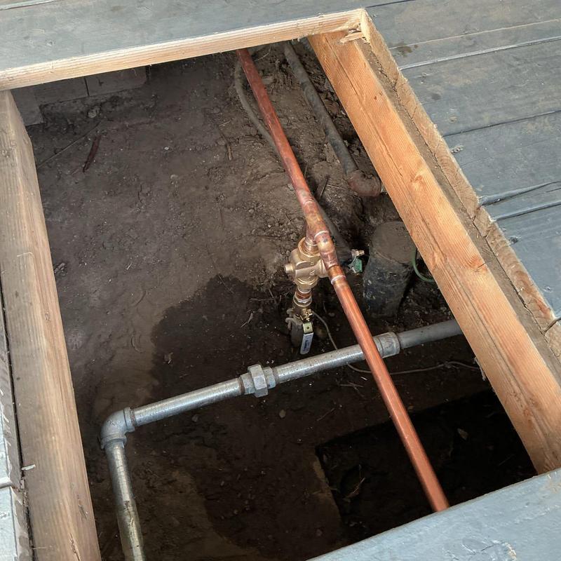 Copper water shut-off valve and pipe underground beneath porch