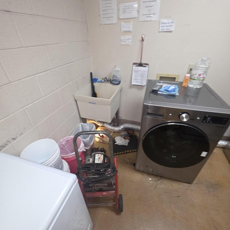 Commercial washer drain with plumbing snake in utility room