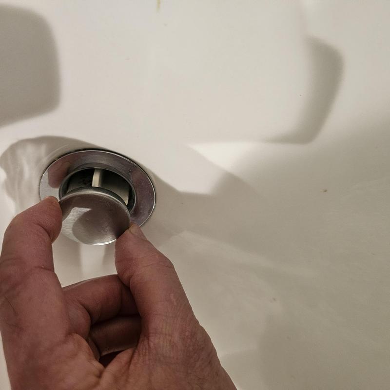 Basin faucet stopper being removed for service