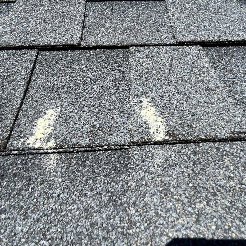 Asphalt shingles with hail damage marked for repair