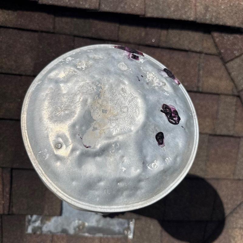 Metal roof vent cap with hail damage on shingles
