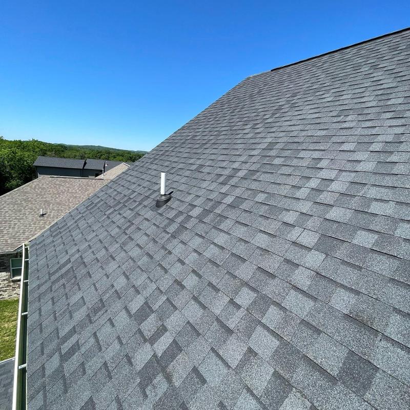 Asphalt shingle roof with vent pipe under clear sky
