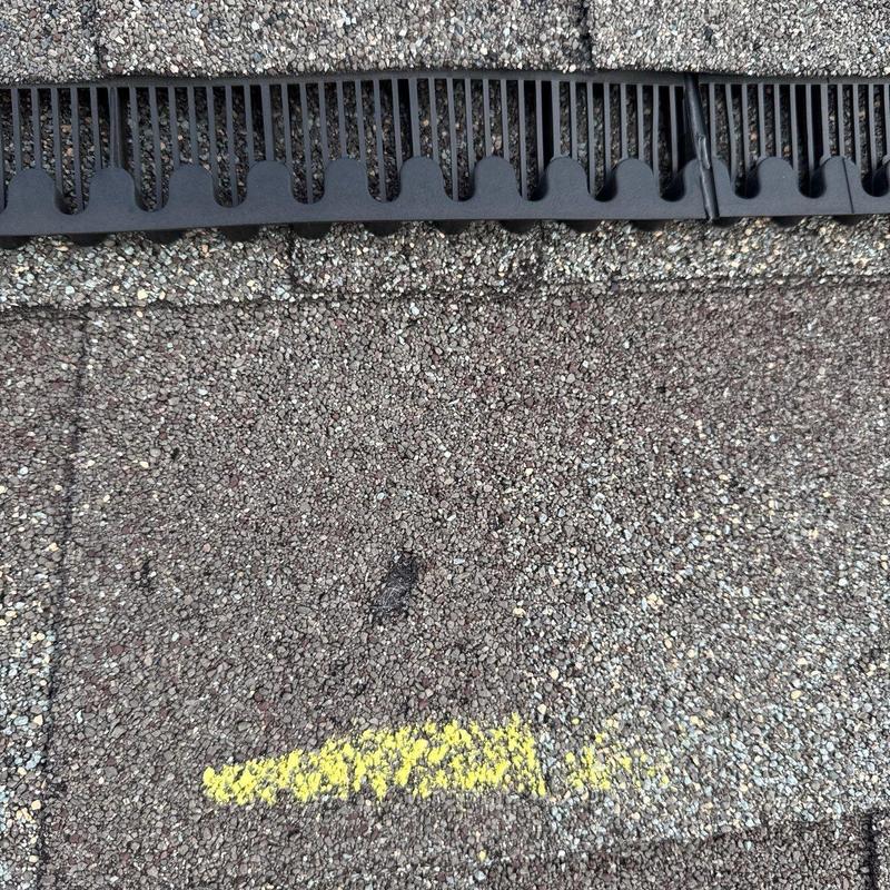 Roof shingle with hail damage near roof vent guard