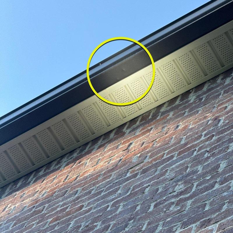 Gutter with minor dent damage near roof soffit