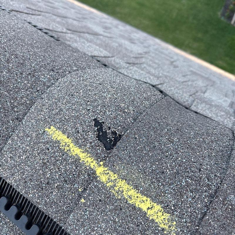 Asphalt shingle with hail damage marked by yellow chalk