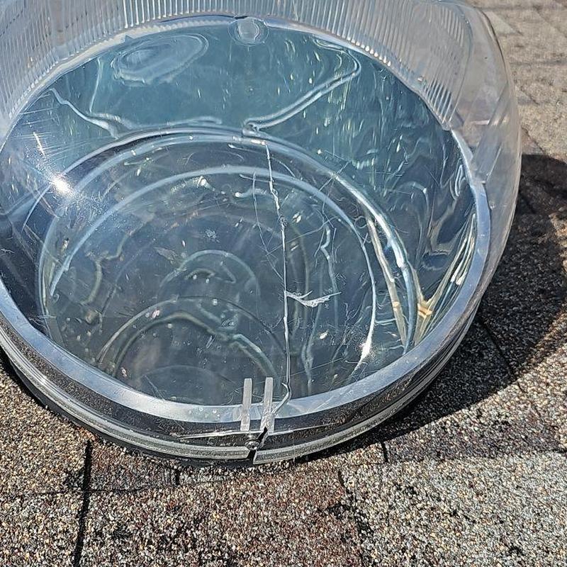 Skylight dome with visible cracks on shingle roof Skylight dome with visible cracks on shingle roof