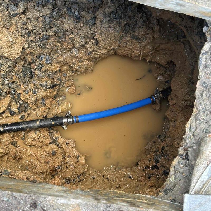 Underground water pipe with clamps in muddy excavation Underground water pipe with clamps in muddy excavation