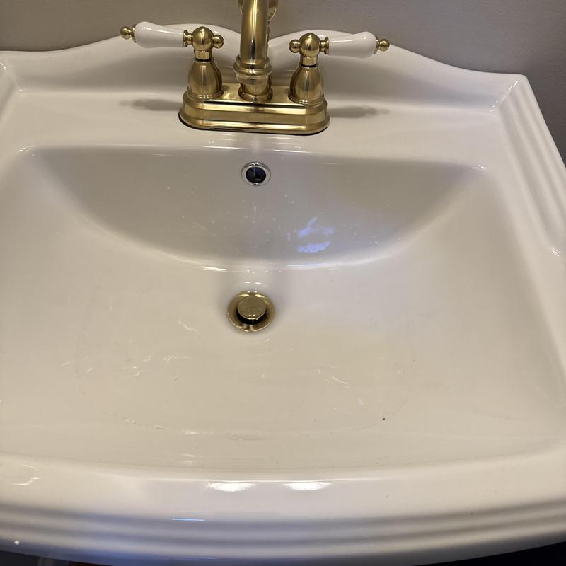 Pedestal sink with brass faucet installed in bathroom