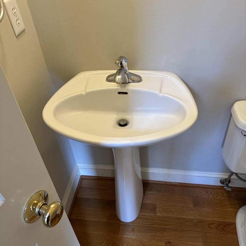 Pedestal sink with faucet in bathroom corner