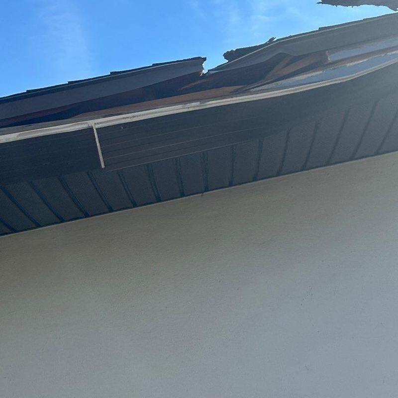 Shingle roof with storm damage and broken fascia board
