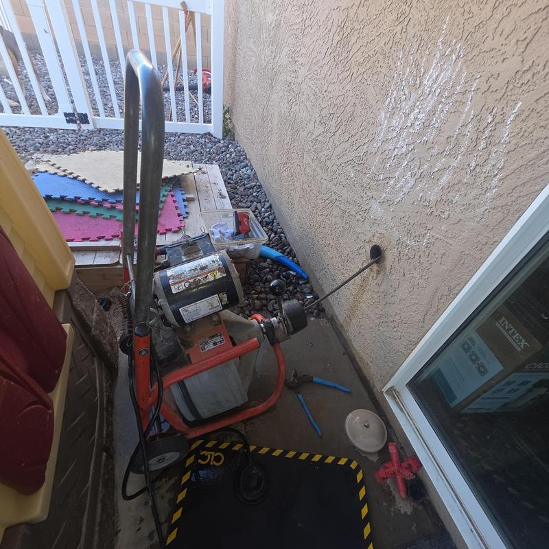 Kitchen sink drain snake clearing blockage from patio clean-out