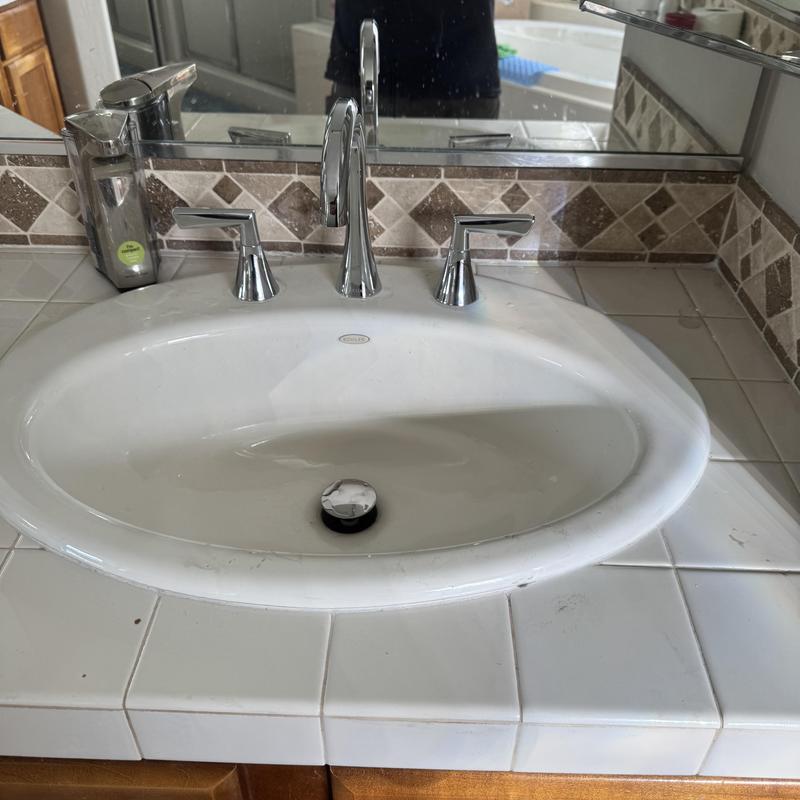 Delta bathroom faucet and sink in tiled countertop