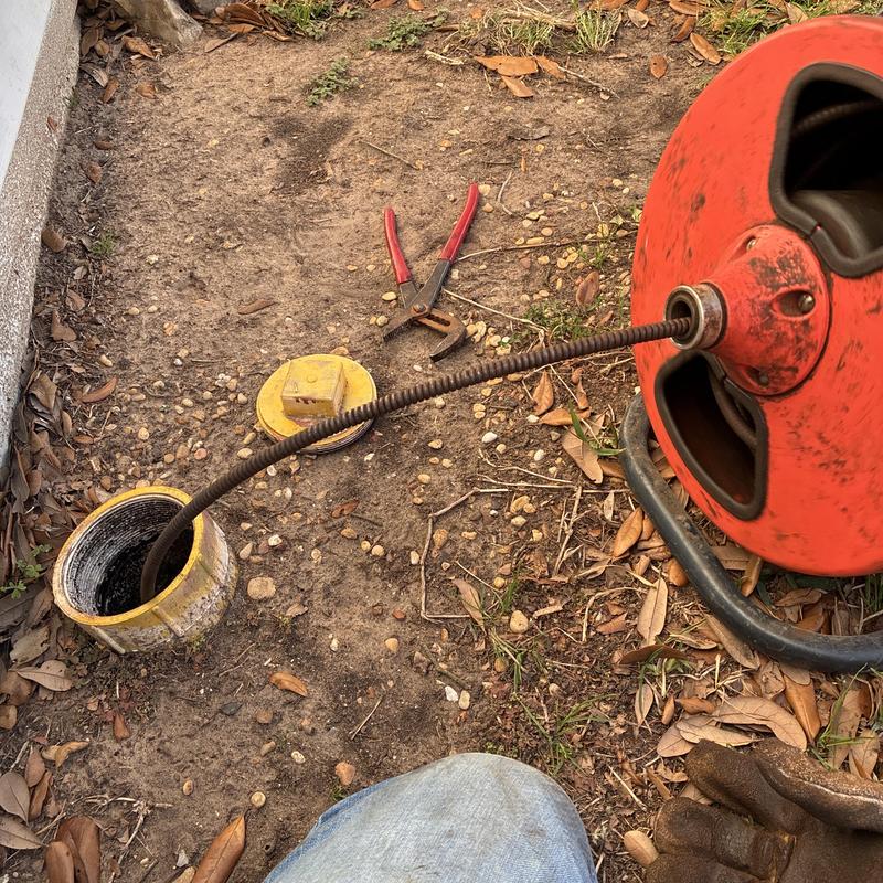 Sewer drain cleaning snake inserted in outdoor cleanout pipe