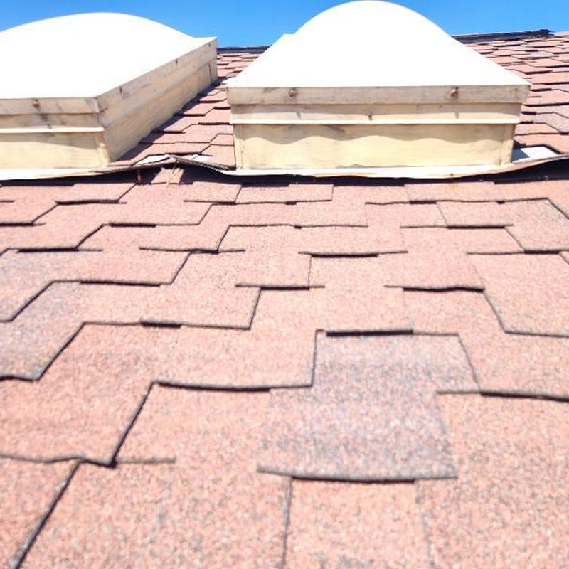 Asphalt shingles with hail damage near skylight flashing