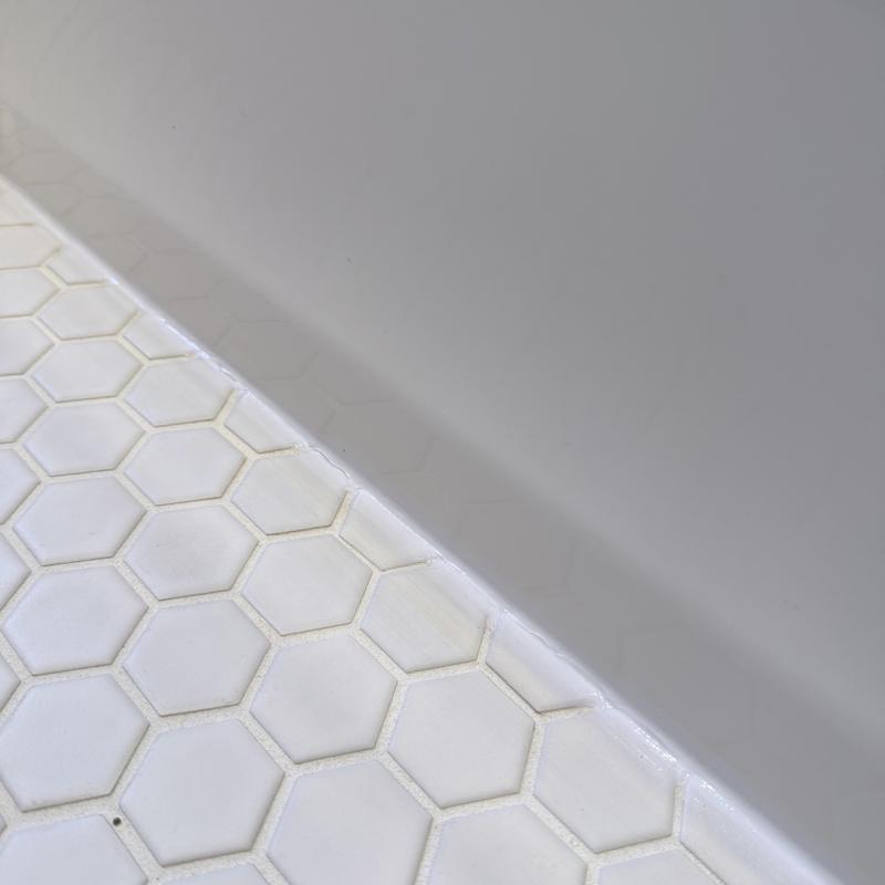 Tub silicone caulking along hex tile bathroom floor edge Tub silicone caulking along hex tile bathroom floor edge