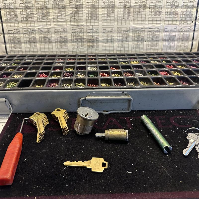 Pin tumblers and key blanks with locksmith tools on mat