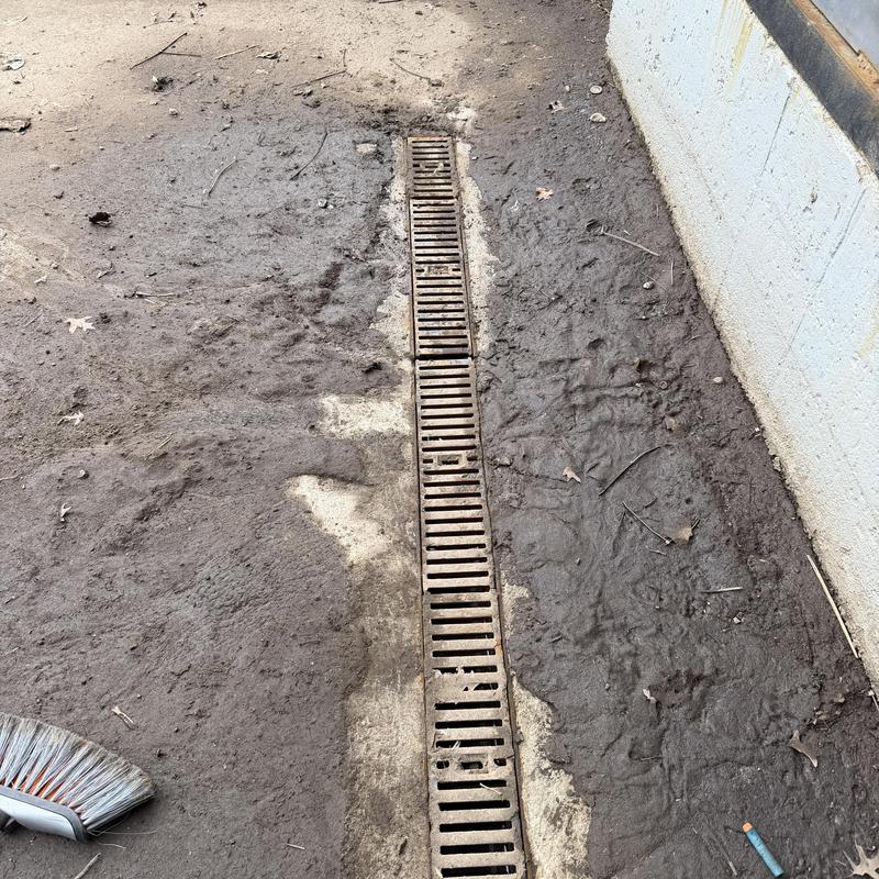 Loading dock drain grate with surrounding dirt and broom Loading dock drain grate with surrounding dirt and broom