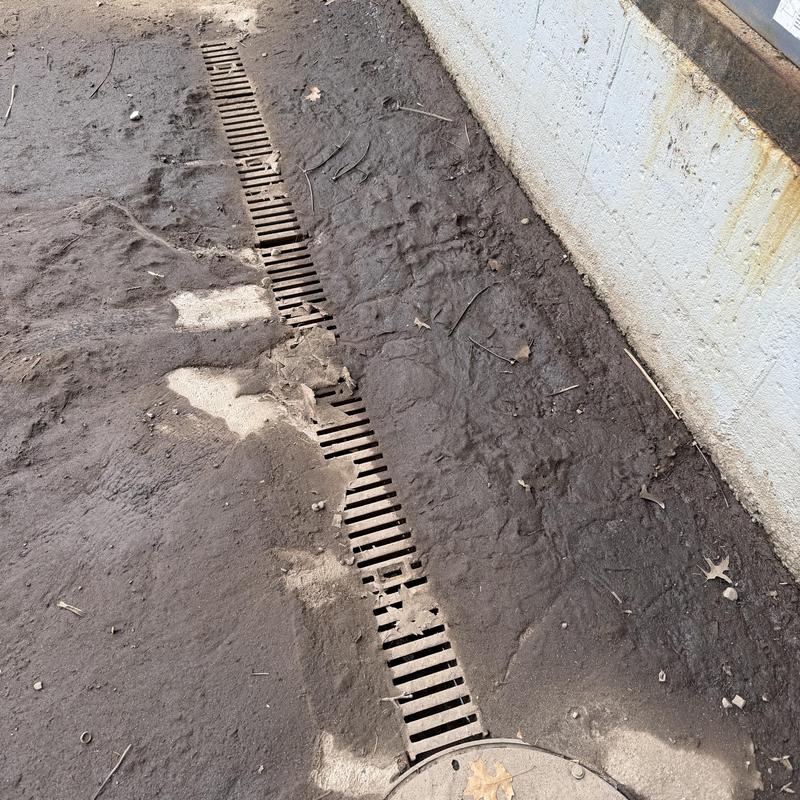 Loading dock drain grate with surrounding dirt buildup Loading dock drain grate with surrounding dirt buildup