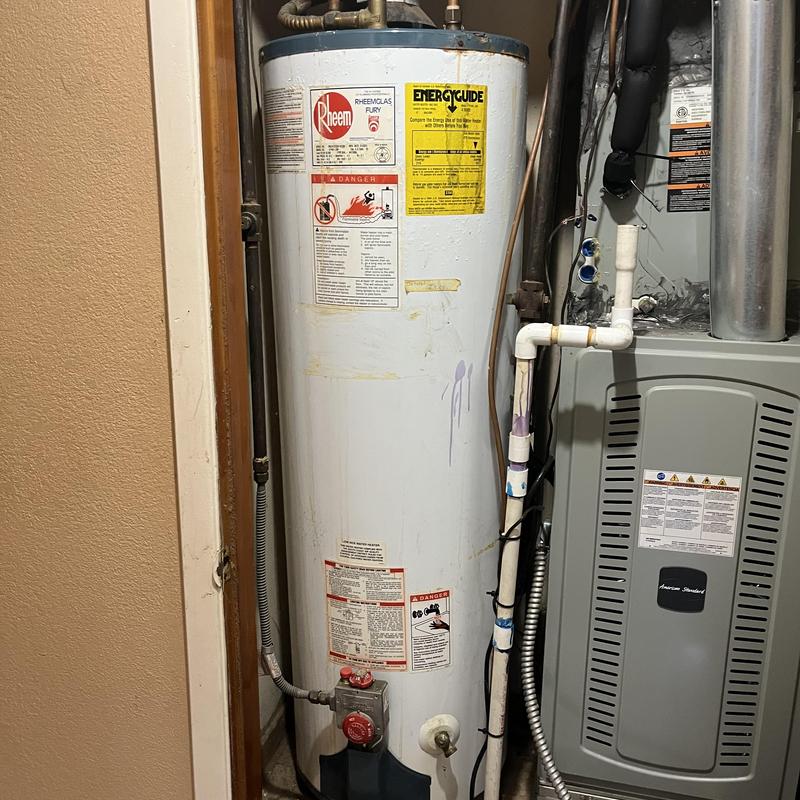 Water heater tank with attached pipes and controls