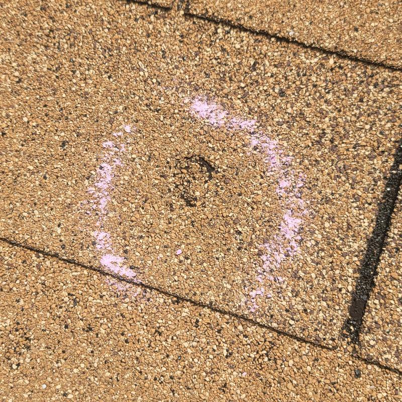 Asphalt roof shingle hail damage marked with chalk