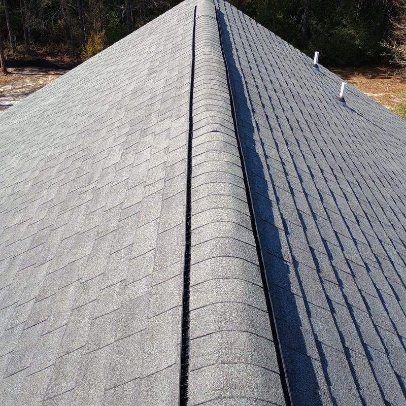 Asphalt shingle roof ridge with vent and nearby pipes Asphalt shingle roof ridge with vent and nearby pipes