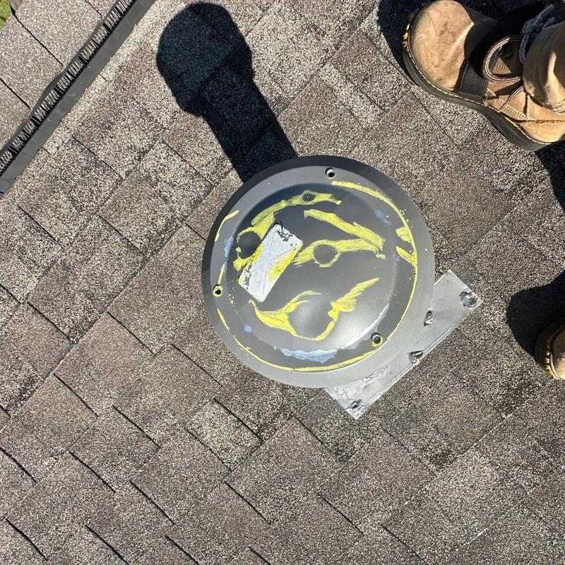 Roof vent cover with hail damage markings on shingles