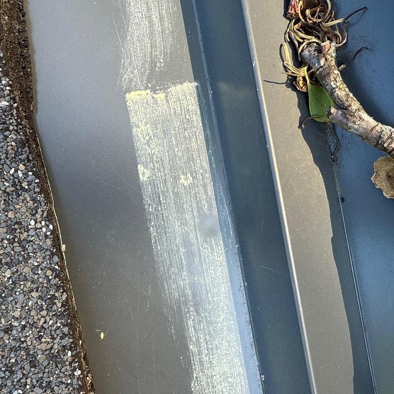 Roof flashing with hail damage and debris on roof slope
