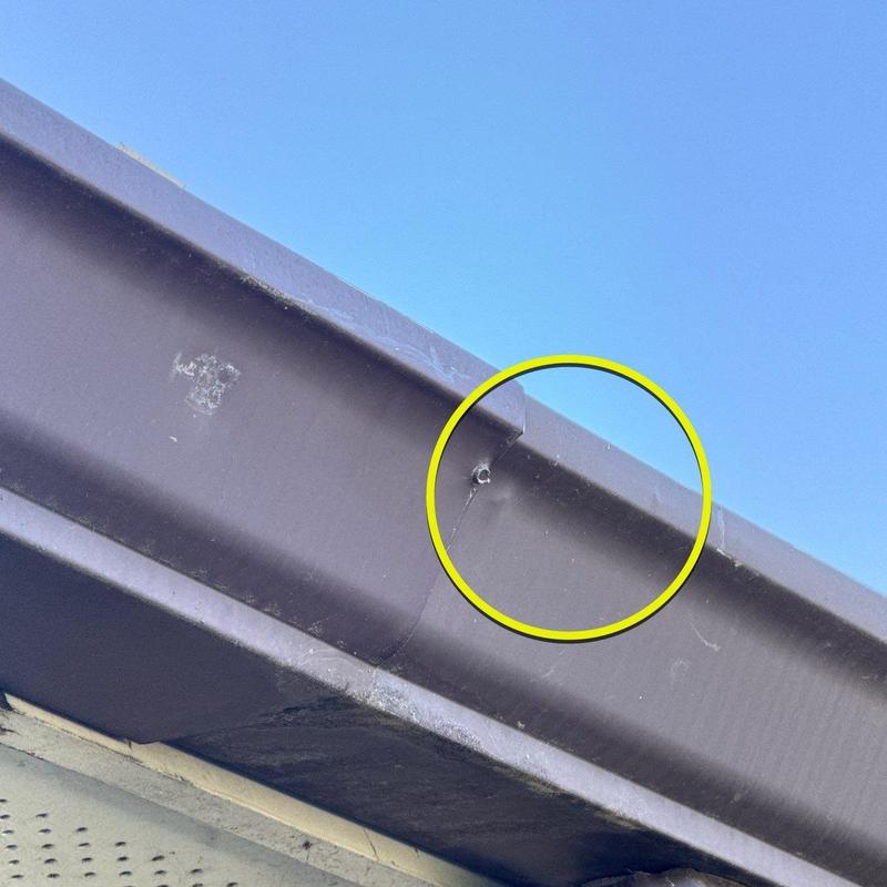 Metal roof flashing with hail damage hole circled