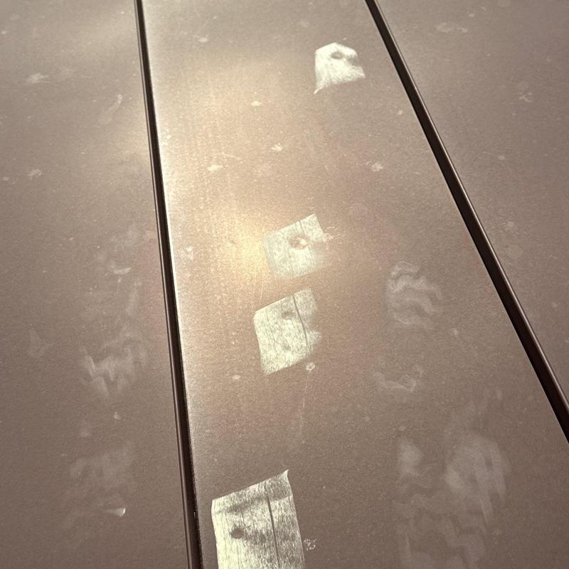 Metal roof panels with hail damage marks under sunlight