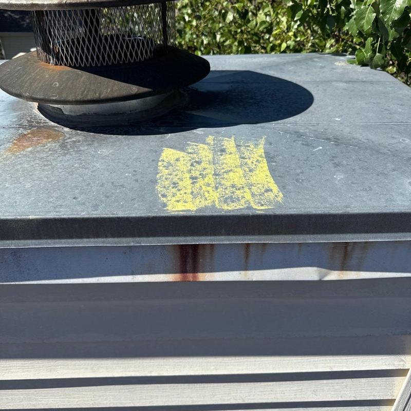 Metal roof vent with rust and yellow marking on top