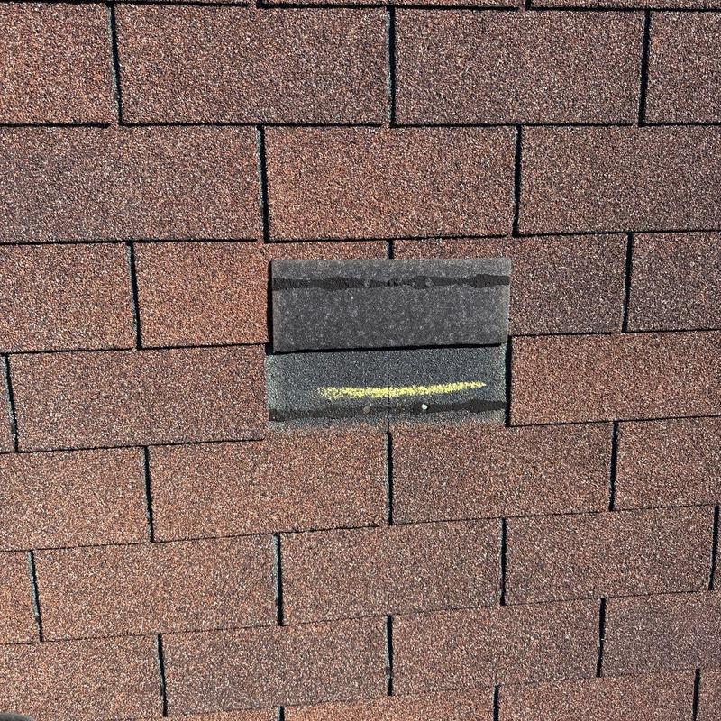 Asphalt roof shingle with hail damage marked in yellow